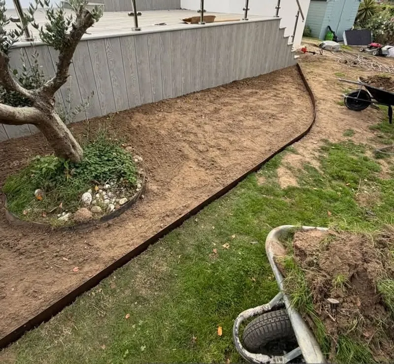 A freshly dug and edged bed curving around a tree in a lawn
